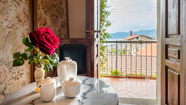 Una habitación con vista a un balcón, una mesa con un florero y una chimenea.