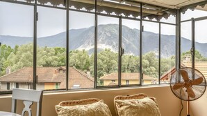 A balcony with wicker chairs and a table, overlooking a mountainous landscape with houses. - Rachele by Interhome (Verbania)