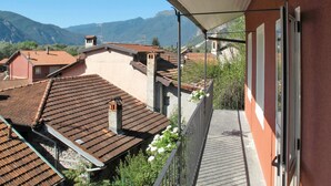 A balcony with a view of terracotta-roofed buildings and mountains in the background. - Rachele by Interhome (Verbania)