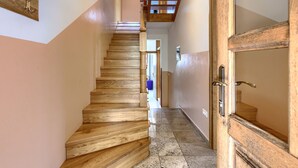 A wooden staircase leading to a landing with a door and a small window.
