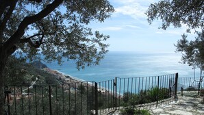 A stone pathway leading to a scenic overlook with a metal fence, overlooking a coastal landscape with buildings and the sea. - Francesca (VGO210) by Interhome (Varigotti)