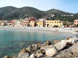 A coastal town with buildings along the beach and rocky shores in the foreground. - Francesca (VGO210) by Interhome (Varigotti)