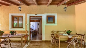 A rustic dining area with wooden tables and benches, a tiled floor, and a wooden ceiling. - Vacation home Jakov by Interhome (Rovinj)
