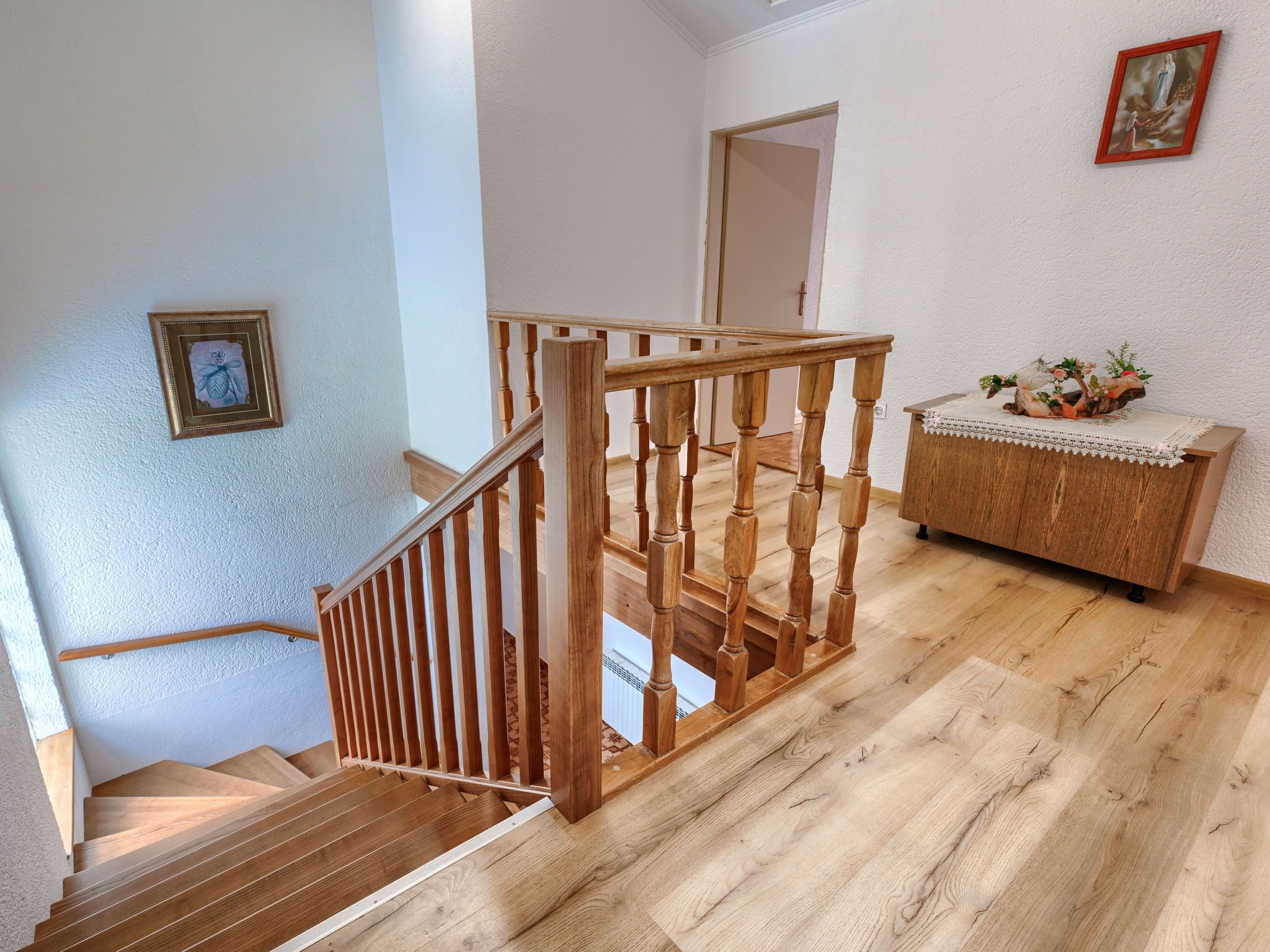 A wooden staircase with a railing leading to a landing.