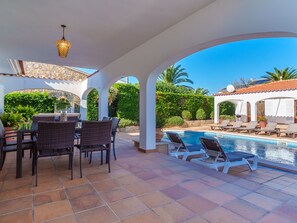A covered outdoor area with a pool, lounge chairs, and a dining table with chairs. - Vacation home Ana I by Interhome (Cala Murada)