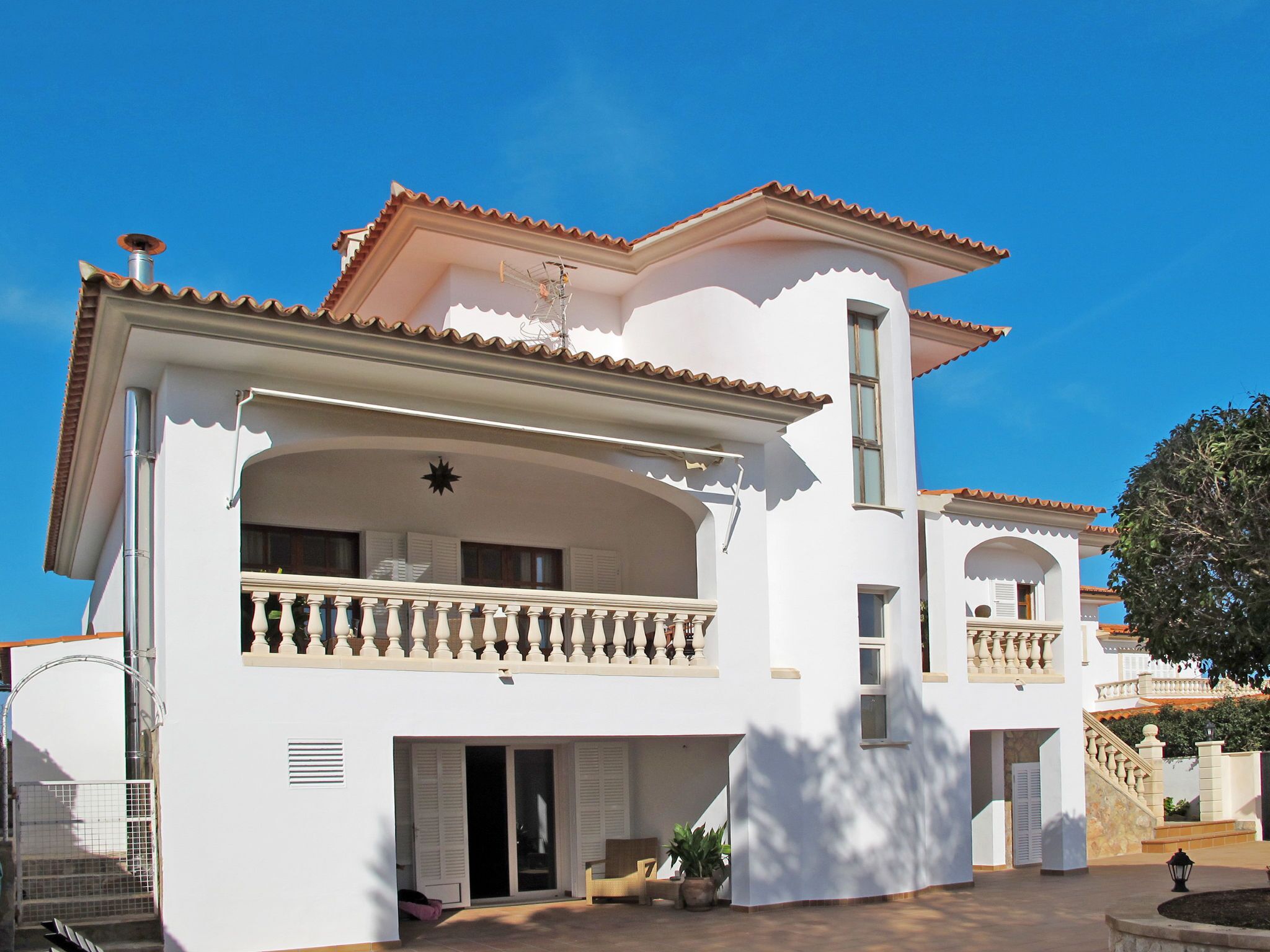 A two-story building with a balcony, a staircase, and a large window.