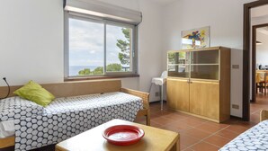 Een kamer met een bed, een klein tafeltje met een schaal, een kast en een raam met uitzicht.