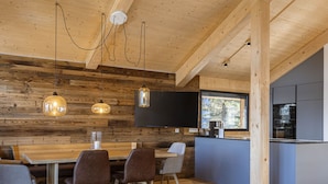Eine moderne Küche mit einem großen Fenster, Holzwänden und einem Essbereich mit einem Holztisch und Stühlen.
