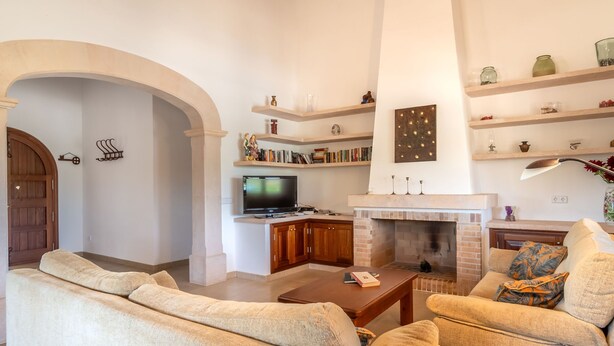 A living room with a fireplace, a television, and a bookshelf. - Jardines by Interhome (Felanitx)