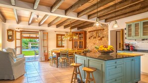A spacious kitchen with a large island, wooden beams on the ceiling, and a view of the outdoors. - Son Viquet by Interhome (Campos)
