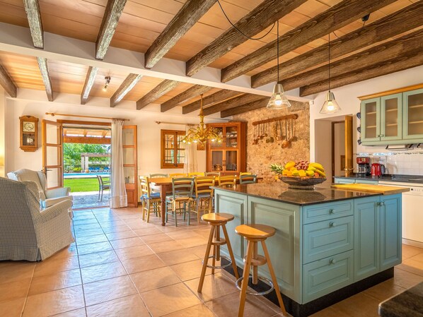 Una cocina amplia con una isla grande, vigas de madera en el techo y vistas al exterior.