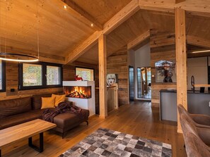 Ein gemütliches Blockhaus-Interieur mit Kamin, Holzwänden, einer Couch und einem Essbereich.
