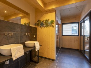 A modern bathroom with two sinks, a large mirror, and a wooden wall. - 02_NTH004_Sup Chalet mit Sauna und Hot Tub 2 Etage by Interhome (Turracher Höhe)