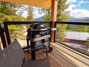 Ein Weber PULSE Grill auf einer Holzterrasse mit Blick auf eine gebirgige Landschaft.