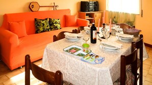 Een eethoek met een tafel voor vier personen, omringd door oranje banken en een houten kast.