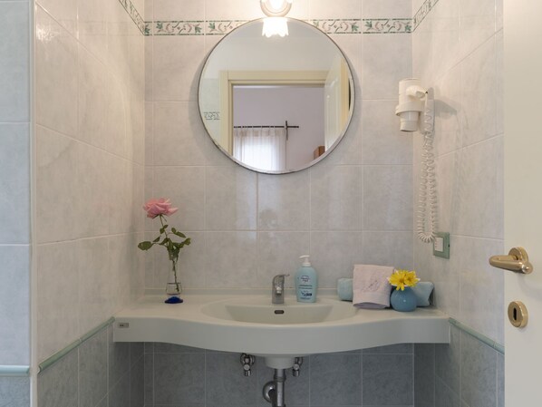 A bathroom with a round mirror, a sink, a towel rack, and a toilet. - Joy (IMP521) by Interhome (Imperia)
