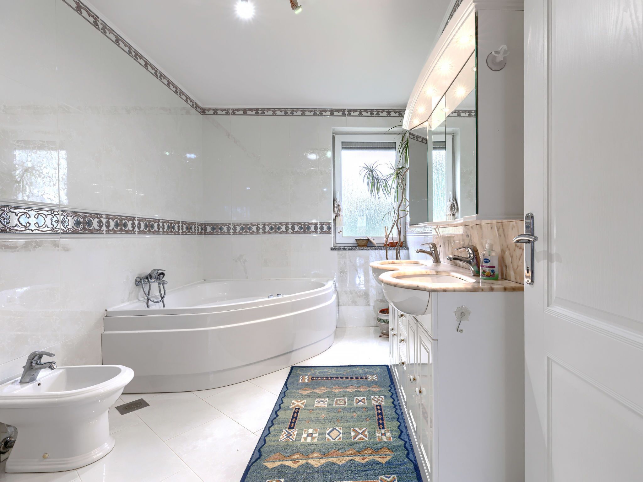 A modern bathroom with a freestanding bathtub, a bidet, and a vanity with a mirror.