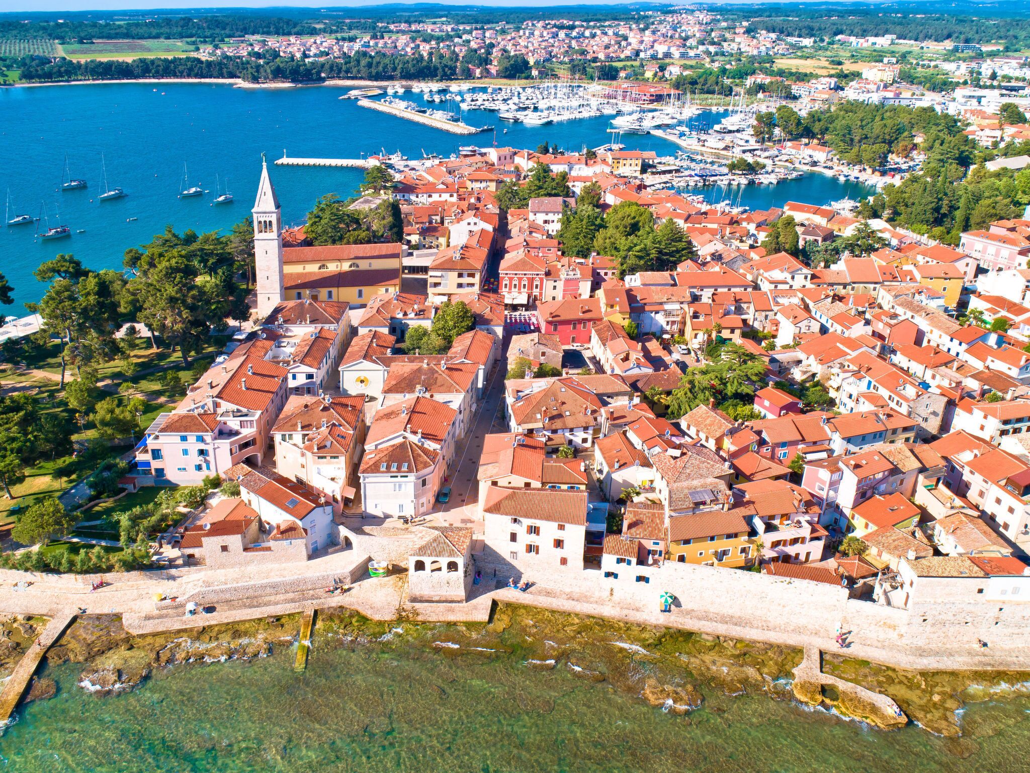 A coastal town with historic buildings, a prominent tower, and a marina.