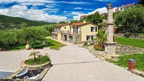 A two-story house with a stone facade, a balcony, and a garden with a fountain. - Freedom (IMP520) by Interhome (Imperia)