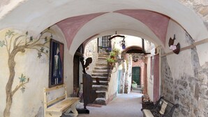 An arched corridor with a bench, a staircase, and a wall with a tree mural. - Il Rifugio (BCM110) by Interhome (Boscomare)