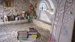 A stone-walled room with bookshelves, a mural, and a wooden door with a bird design. - Il Rifugio (BCM110) by Interhome (Boscomare)
