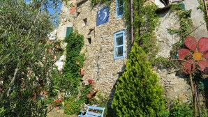 A stone building with a rustic charm, featuring a wooden bench and potted plants. - Il Rifugio (BCM110) by Interhome (Boscomare)