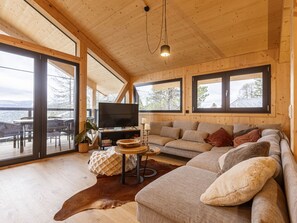 Una sala de estar acogedora con un sofá grande, una televisión y un techo de madera.