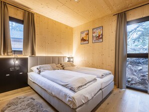 Ein Schlafzimmer mit einem Doppelbett, Holzwänden, einem Fenster mit Vorhängen und einem Poster an der Wand.