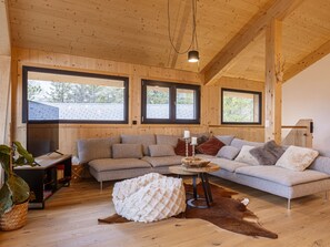 Una sala de estar acogedora con un sofá modular, un televisor de pantalla plana y un ventanal grande.