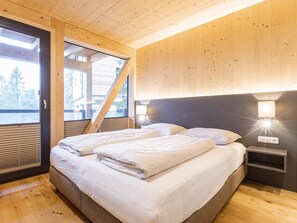 A bedroom with a bed, two bedside tables, a window, and a wooden ceiling.