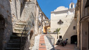 A narrow cobblestone street flanked by historic stone buildings with a staircase leading to an upper level. - Le Antiche Volte (SLR215) by Interhome (San Lorenzo al Mare)