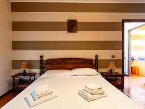 Une chambre d’hôtel avec un grand lit, deux tables de chevet avec des lampes, une tête de lit en bois et un tableau au mur.