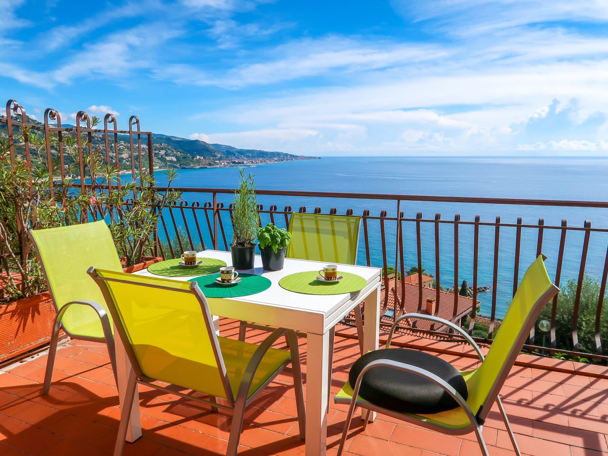 Une terrasse avec une table dressée pour deux personnes, des chaises et des plantes en pot.