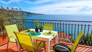 A terrace with a table set for two, chairs, and potted plants. - Paradise View by Interhome (Ventimiglia)