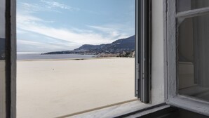 En utsikt från ett fönster med utsikt över en strand och ett berg i bakgrunden.