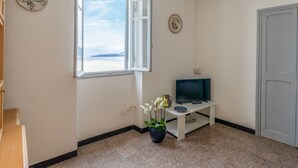 Ett rum med ett stort fönster, en tv på ett litet bord och en dörr.