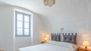 Ett sovrum med en säng, två sängbord, ett fönster och en taklampa.