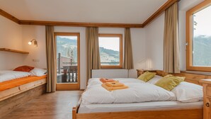 Ein Schlafzimmer mit einem hölzernen Bett, einem Nachttisch, einem Fenster mit Bergblick und einem Balkon.