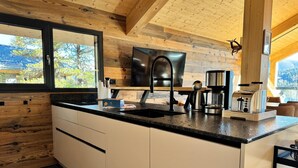 Una cocina moderna con una isla grande, electrodomésticos integrados y vistas al exterior.