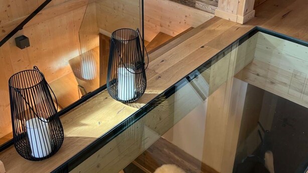 Un interior moderno con una mesa de vidrio, suelo de madera y una pieza de arte mural original.