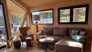 Interior acogedor de una cabaña con sofá, sillón y una mesa redonda.