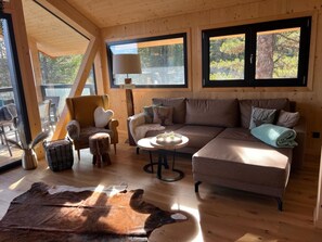 L’intérieur d’un chalet chaleureux, avec un canapé, un fauteuil et une table ronde.