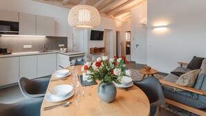 A modern kitchen with white cabinets, a dining area with a round table, and a living room with a sofa. - Das Georgen, Großglockner+Kitzsteinhorn by Interhome (Bruck)