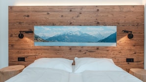 A bedroom with a wooden headboard, a large framed picture of a mountain lake, and two bedside tables. - Das Georgen, Großglockner+Kitzsteinhorn by Interhome (Bruck)