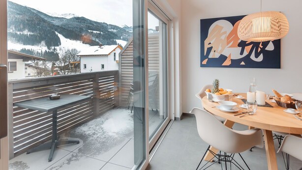 A modern dining area with a large window overlooking a snowy mountain landscape. - Das Georgen, Großglockner+Kitzsteinhorn by Interhome (Bruck)
