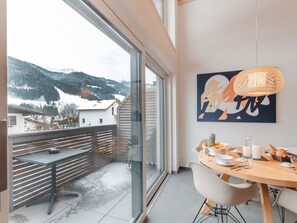 Ett modernt matområde med ett stort fönster som vetter ut mot ett snötäckt berglandskap.