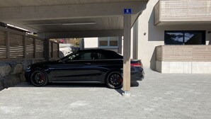 Un coche negro estacionado debajo de un edificio con un cartel que indica '6 Lindenstrasse'.