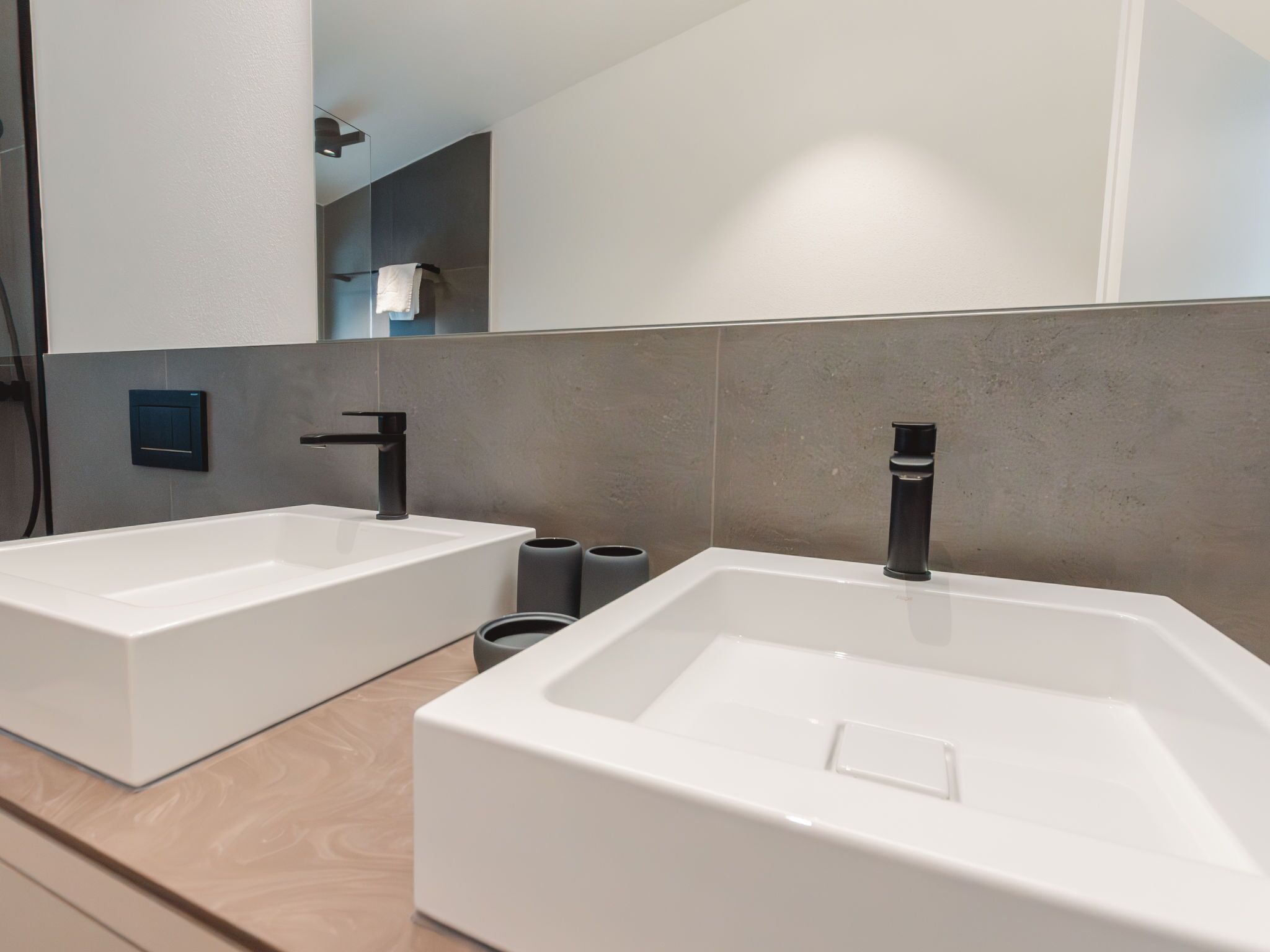 A modern bathroom with two white sinks, a large mirror, and a wooden vanity.
