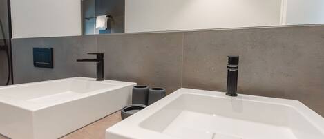 A modern bathroom with two white sinks, a large mirror, and a wooden vanity.