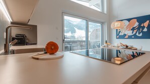 A modern kitchen with a large window, a coffee machine, and a pumpkin on the counter. - Das Georgen, Kitzsteinhorn by Interhome (Bruck)